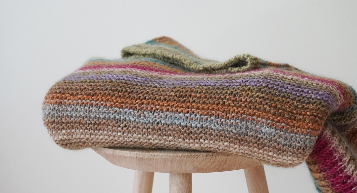 Gestreifter handgestrickter Pullover über Hocker